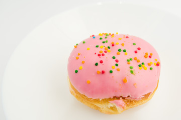 Pink round donut on white plate on white background