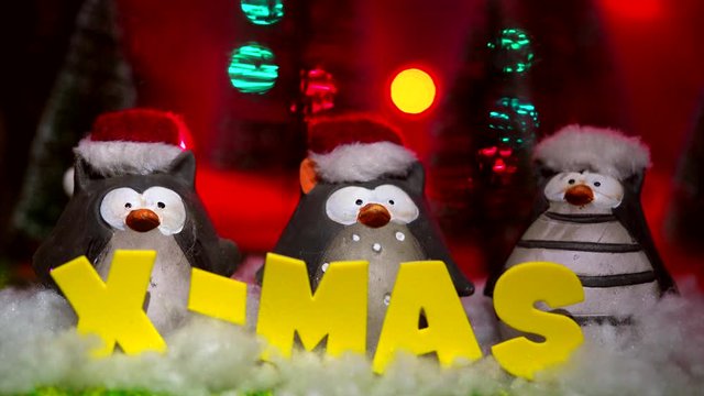 decoration penguin puppets with christmas letters. X-Mas stands sign in fake snow. The penguins wear santa claus hats