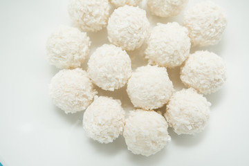 Chocolate covered coconut candies on white plate isolated on white background. Truffle candy set. Selective focus