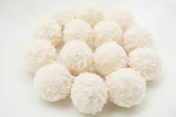 Chocolate covered coconut candies on white plate isolated on white background. Truffle candy set. Selective focus
