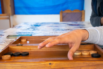 Playing backgammon on a wooden table with dices.