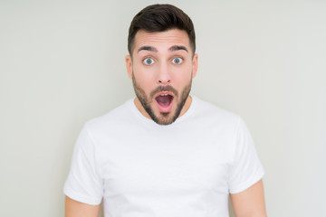 Young handsome man wearing casual white t-shirt over isolated background afraid and shocked with surprise expression, fear and excited face.