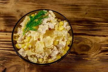 Festive salad with chicken breast, sweet corn, canned pineapple, cheese and mayonnaise on wooden table