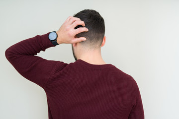 Young handsome man wearing a sweater over isolated background Backwards thinking about doubt with hand on head