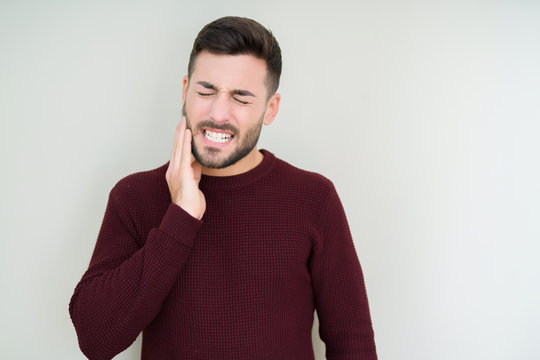 Young handsome man wearing a sweater over isolated background touching mouth with hand with painful expression because of toothache or dental illness on teeth. Dentist concept.