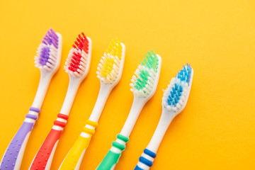 set of plastic toothbrushes on yellow background