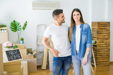Beautiful young couple moving to a new house, smiling happy arround cardboard boxes