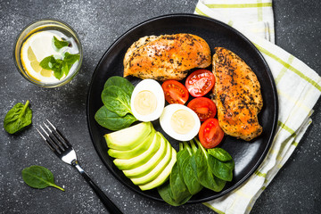 Buddha bowl quinoa salad with chicken and vegetables on black.