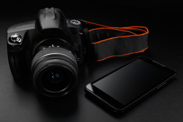 Professional digital slr camera and smartphone on black background