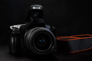 Professional digital SLR camera with opened built-in flash on black background.