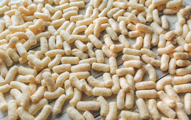 Lots of yellow corn sticks on a white wooden background. Delicious airy dessert. Concept and picture, copy space. Baby food. Subject photography.