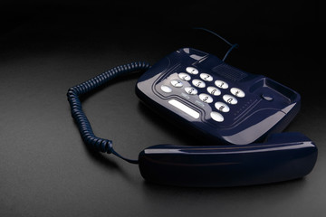 Outdated push-button telephone with handset on black background