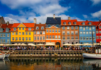 View of Nyhavn pier with color buildings, ships, yachts and other boats in the Old Town of Copenhagen, Denmark. Blue sky is in the background.