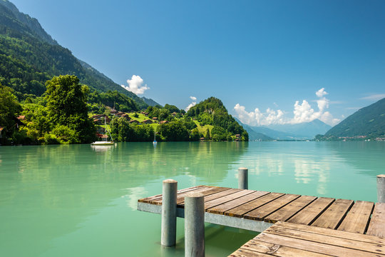 View of Brienz lake with clear turquoise water. Wooden pier. Traditional wooden houses on the shore of Brienz lake in the village of Iseltwald, Switzerland © bbgreg