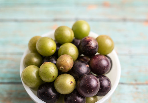 Muscadine grapes are also known as swamp grapes, Florida grapes in a bowl on wood background
