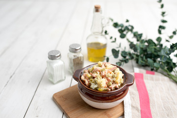Bowl of traditional Russian salad called Olivie, Russian New Year or Christmas salad on wooden background. Salad from cooked vegetables. Potato salad. 