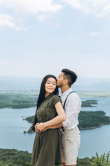 A young couple hugs and a man kisses a woman.