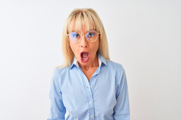 Middle age businesswoman wearing glasses and shirt standing over isolated white background scared in shock with a surprise face, afraid and excited with fear expression