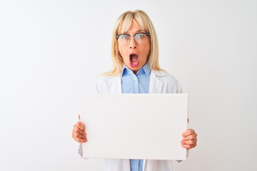 Middle age scientist woman wearing glasses holding banner over isolated white background scared in shock with a surprise face, afraid and excited with fear expression