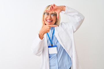 Middle age scientist woman wearing glasses and id card over isolated white background smiling making frame with hands and fingers with happy face. Creativity and photography concept.