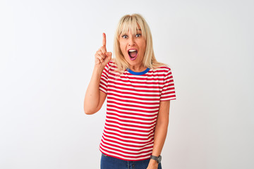 Middle age woman wearing casual striped t-shirt standing over isolated white background pointing finger up with successful idea. Exited and happy. Number one.