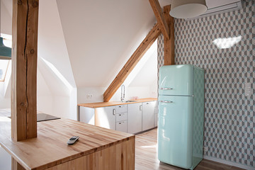 Retro refrigerator in bright attic kitchen in loft apartment