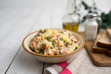 Bowl of traditional Russian salad called Olivie, Russian New Year or Christmas salad on wooden...