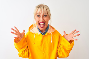 Middle age woman wearing yellow rain coat standing over isolated white background celebrating crazy and amazed for success with arms raised and open eyes screaming excited. Winner concept