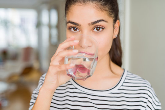 Beautiful young woman drinking a fresh glass of water at home