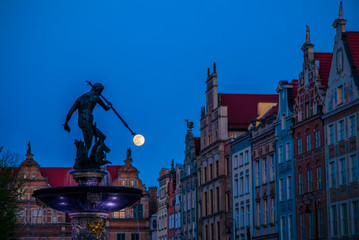 Evening view of Neptune's Fountain with bronze statue in old town in Gdansk Poland. Moon on the trident, hunt moon © Oleksandr