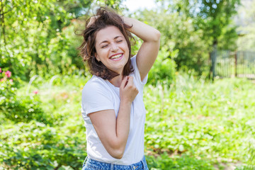 Happy girl smiling outdoor. Beautiful young brunete woman with brown hair resting on park or garden...