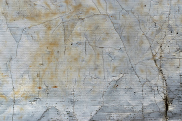 old dirty torn canvas of white, gray, yellow color with protruding fibers and holes as an abstract background