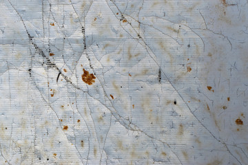old dirty torn canvas of white, gray, yellow color with protruding fibers and holes as an abstract background