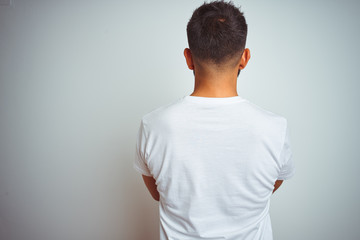 Young indian man wearing t-shirt standing over isolated white background standing backwards looking...