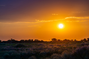 Bright sun in an orange sky with clouds at sunset