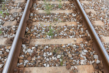 Closeup view of older train tracks with weeds. Concept of  railroad maintenance.