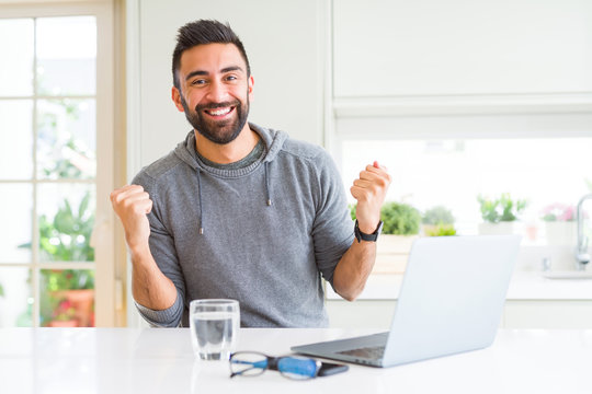 Handsome hispanic man working using computer laptop celebrating surprised and amazed for success with arms raised and open eyes. Winner concept.