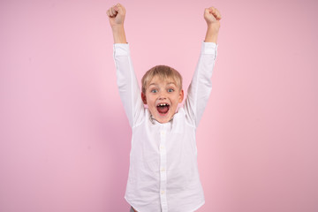 Portrait of cute trendy stylish kid astonished impressed aims contest lottery fortune, scream omg, wow, unbelievable unexpected raise fists shout wear white modern outfit isolated pink background