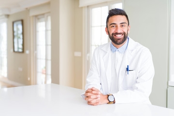 Handsome hispanic doctor or therapist man wearing medical coat at the clinic with a happy and cool...