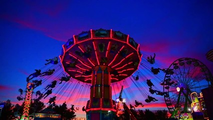 Swing Carousel spins in the nigh sky as the sun goes down creating the perfect sunset - Powered by Adobe