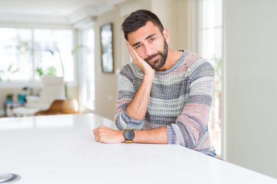 Handsome hispanic man wearing casual sweater at home thinking looking tired and bored with depression problems with crossed arms.
