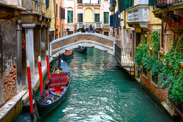 Fototapeta na wymiar Narrow canal with gondola and bridge in Venice, Italy. Architecture and landmark of Venice. Cozy cityscape of Venice.