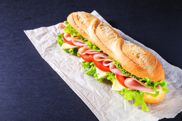 Big submarine sandwich with ham, cheese and salad