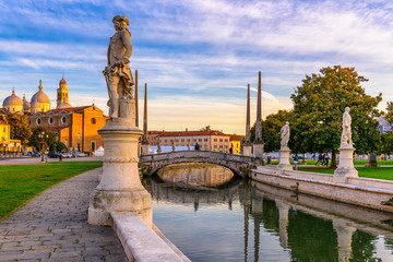 View of canal with statues on square Prato della Valle and Basilica Santa Giustina in Padova (Padua), Veneto, Italy - obrazy, fototapety, plakaty