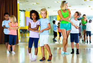 Group of children practicing vigorous jive movements in dance cl