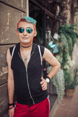 Homosexual male with stylish hairstyle and gay glasses posing at flowers boutique on background