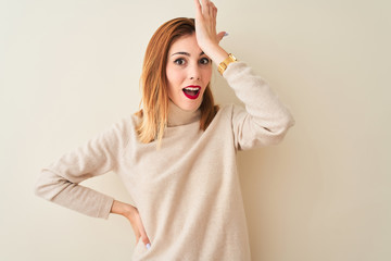 Redhead woman wearing elegant turtleneck sweater standing over isolated white background surprised...