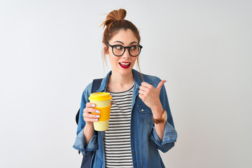 Beautiful redhead student woman drinking take away coffee over isolated white background pointing and showing with thumb up to the side with happy face smiling