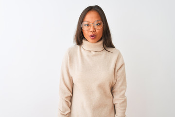 Fototapeta premium Young chinese woman wearing turtleneck sweater and glasses over isolated white background afraid and shocked with surprise expression, fear and excited face.