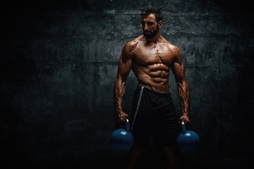 Fototapeta na wymiar Strong Muscular Men Exercise With Kettlebells as part of His Cross Workout